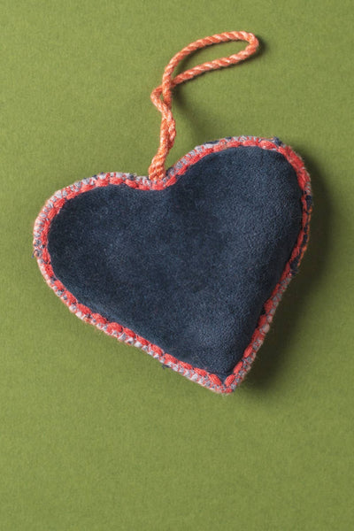 Back of embroidered heart-shaped ornament on a green background