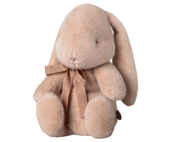 Plush pink bunny toy with a bow on a white background