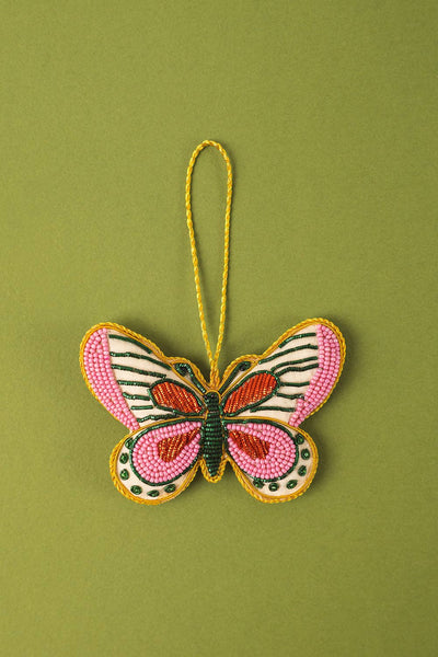 Butterfly-shaped ornament with pink and green design on a green background