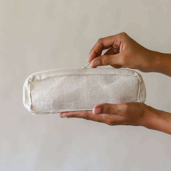 Person holding a white mesh pouch against a plain background