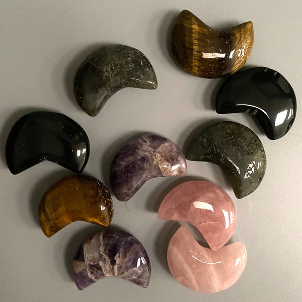 Collection of semi-precious crescent shaped stones on a grey surface