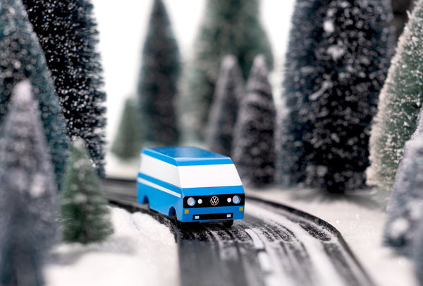 Model van on a miniature road with snow-covered trees in the background