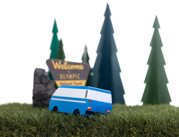 Model bus in front of a 'Welcome to Olympic National Park' sign with trees in the background