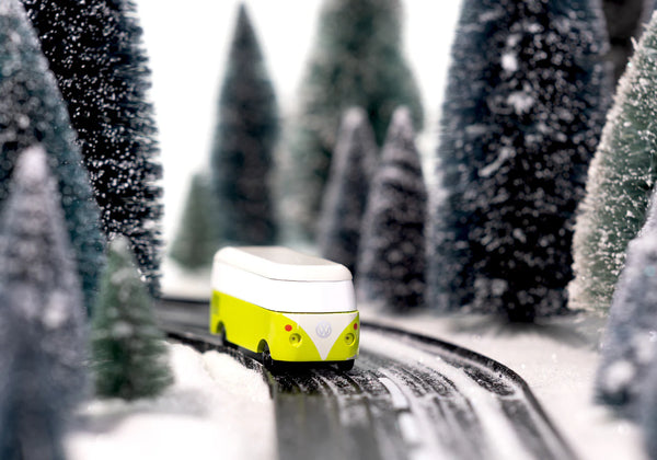 Model bus on a track surrounded by snow-covered trees