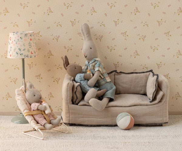 Toy bunnies set up in a playful position with dolls house furniture