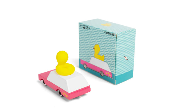 Small toy car with a yellow duck on top next to its packaging on a white background