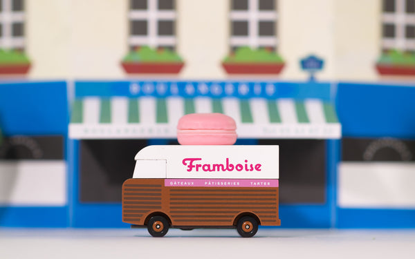 Toy ice cream truck with 'Framboise' branding in front of a blurred storefront