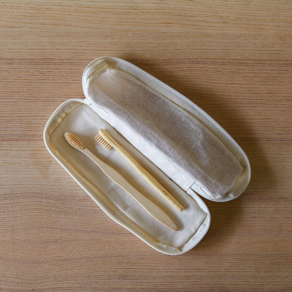 Open beige case with two toothbrushes on a wooden surface