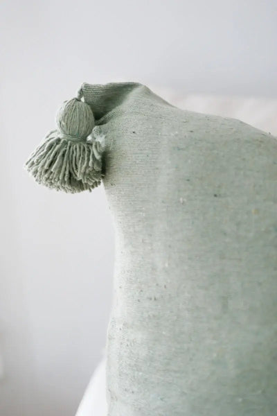 Textured green pillow with a tassel on a white background