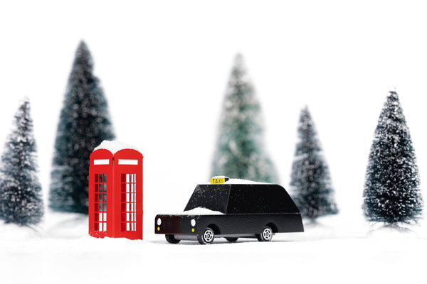 Model black taxi and red telephone box with snow-covered trees in the background