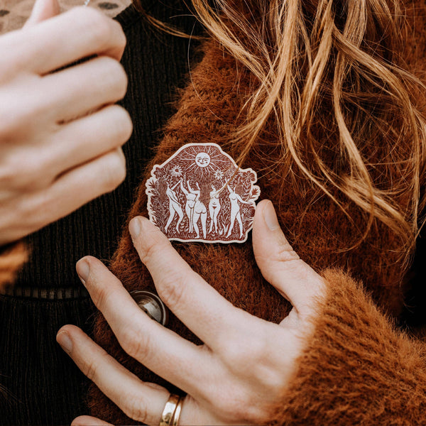Person wearing a brown jacket with a decorative brooch on the chest.