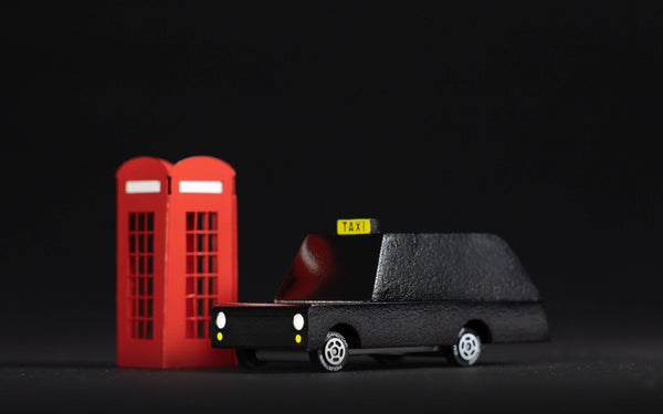 Model of a black taxi and red telephone booth on a black background