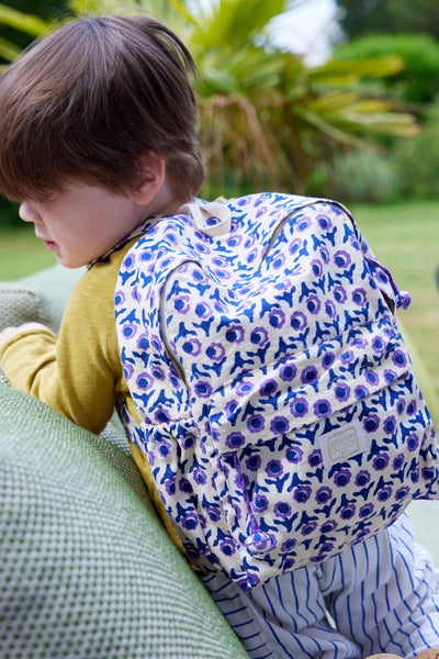 Child wearing a blue floral backpack outdoors