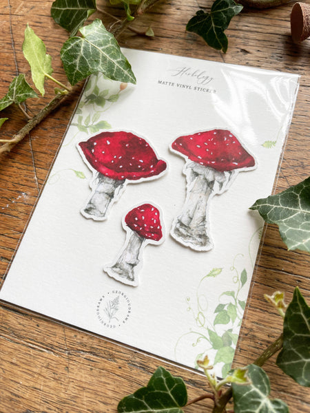 Set of mushroom-shaped stickers on a sheet with green leaves around