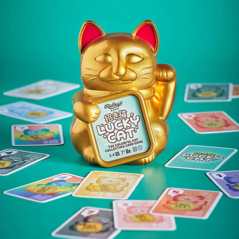 Gold Lucky Cat figurine with trading cards on a teal background