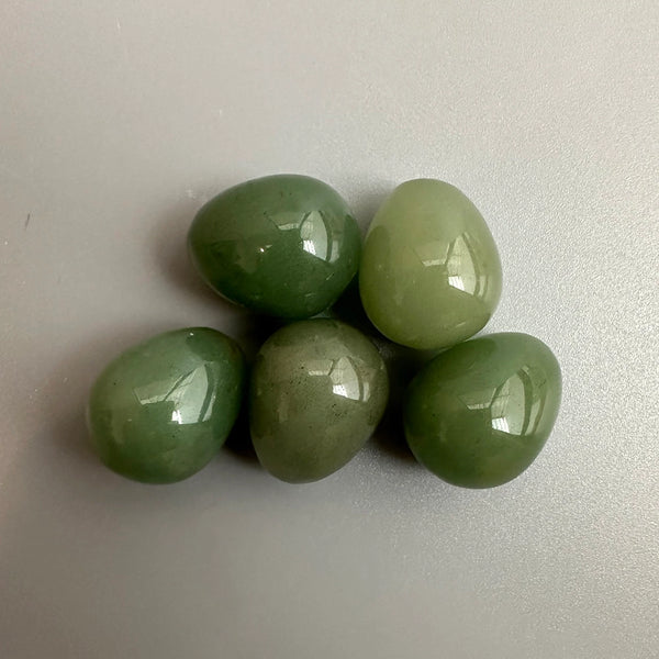 Five green gemstones on a light grey background