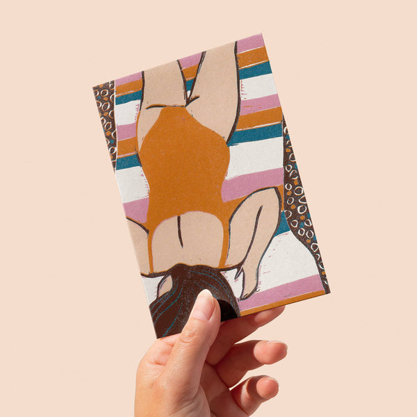 Hand holding a small rectangular object with abstract art design on a beige background