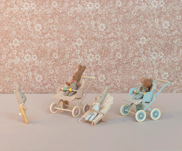 Wooden toy figures of bunnies with strollers on a floral background