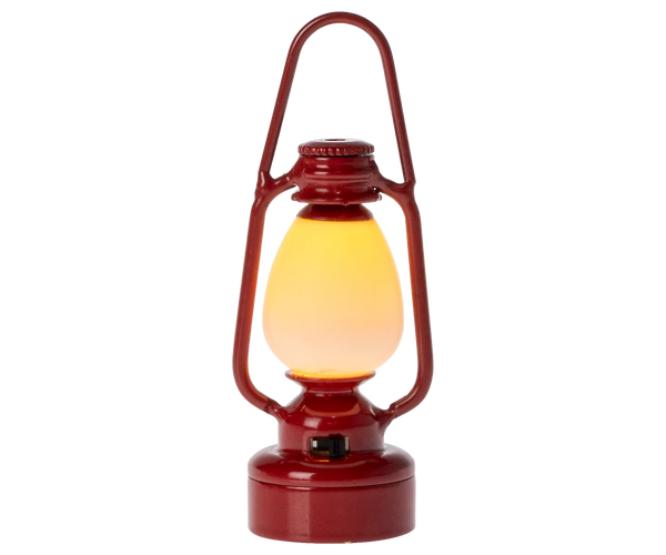 Red miniature toy lantern with a glowing yellow light on a white background