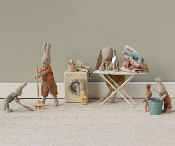 Set of toy animals engaged in household activities on a neutral background