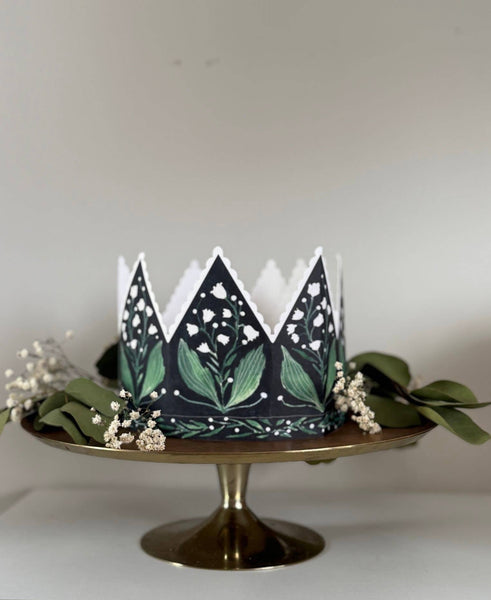 Decorative paper crown with green leaf pattern on a white background