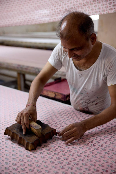 Man working with a wooden tool on a floral fabric surface