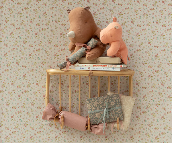 Two plush animals on a small wooden shelf against a floral wallpaper background