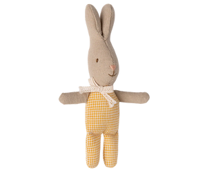 Stuffed rabbit toy with beige body and yellow checkered onesie on a white background
