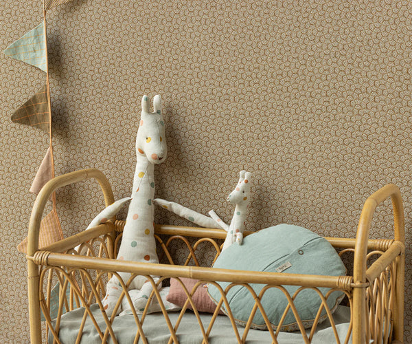 Children's room with a rattan crib, plush toys, and decorative elements against a patterned wall.