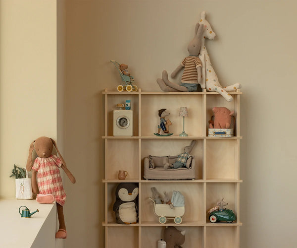 Wooden shelf with various toys and decorative items against a beige wall