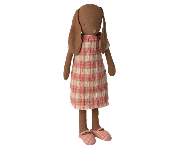 A bunny doll with long floppy ears, brown fabric skin, and a red and cream plaid dress, standing against a plain white background.
