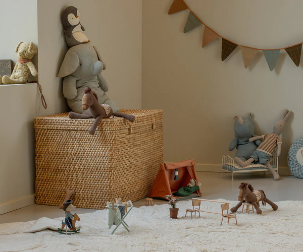 Children's toys and playset in a room with a woven basket and stuffed animals.