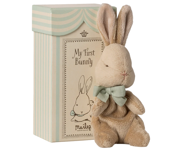 Stuffed bunny toy with a bow tie next to a decorative box labeled 'My First Bunny' on a white background.