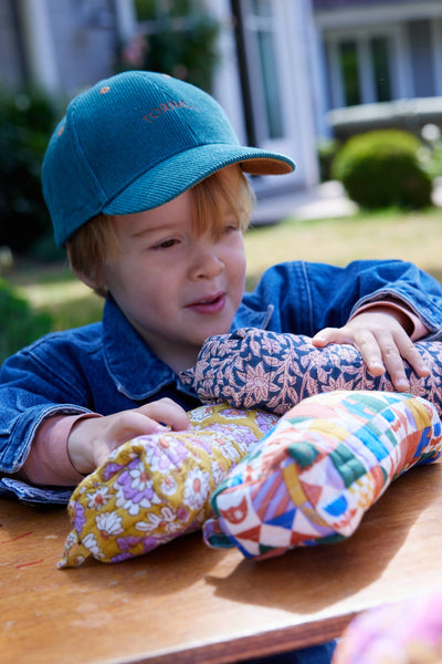 Child playing with colorful fabric pencil cases outdoors