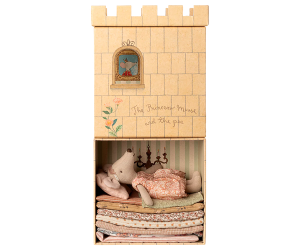 Wooden castle toy with a princess mouse inside on a bed of stacked mattresses on a white background