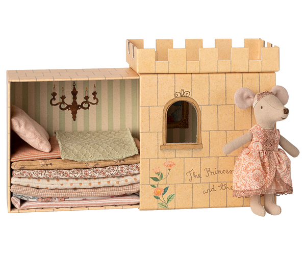 Wooden castle toy with bedding and a mouse doll in a dress on a white background