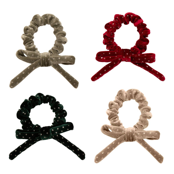 Four velvet hair scrunchies with bow designs in different colours on a white background.