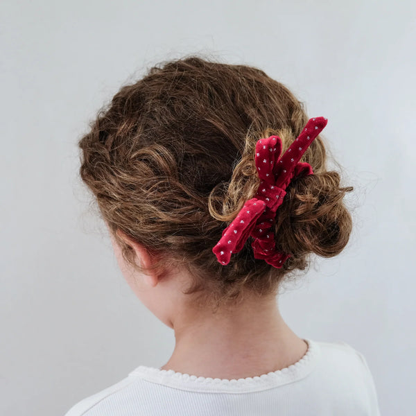 Person with a red hair accessory in their hair against a plain background