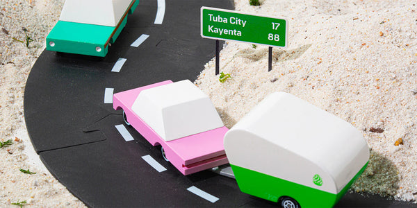 Pink toy car pulling a trailer on a play backdrop