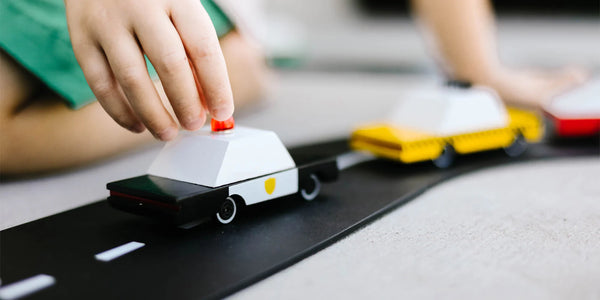 Small model of a police car and taxi being played with by a child on the floor