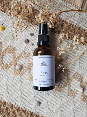 Brown spray bottle labeled 'flow' on a textured surface with dried flowers.