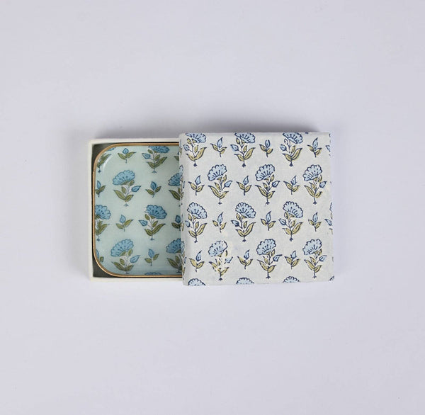 A set of 2 floral enamelled iron coasters shown in their open square presentation box on a plain light background.