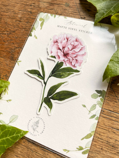 Floral sticker on a white sheet with green leaves on a wooden surface