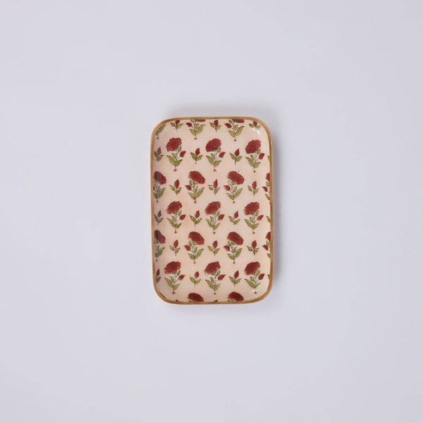 A rectangular enamelled iron tray with rounded corners, featuring a repeating floral pattern of red flowers and green leaves on a light pink background, with a gold coloured trim.