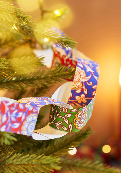 Decorative paper chain on a Christmas tree with a warm, blurred background