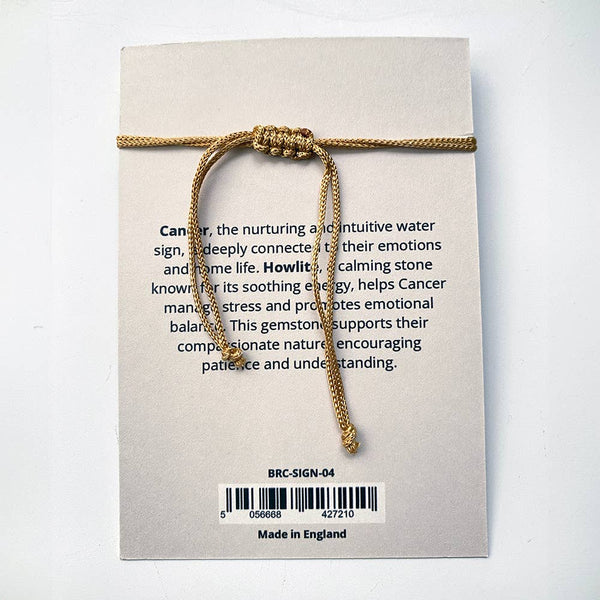 Gold bracelet on a card with text about the sign Cancer and its connection to water.