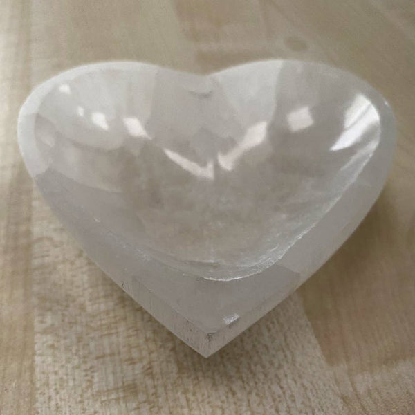 Heart-shaped white bowl on a wooden surface