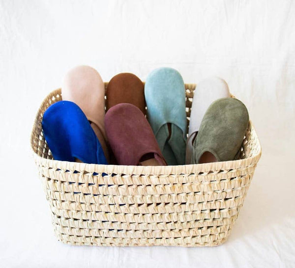 Woven basket with colorful slippers on a white background