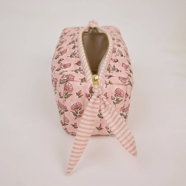 Pink floral-patterned pouch with a gold zipper on a white background