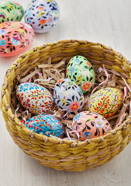 Decorative Easter eggs with floral patterns in a woven basket on a light background